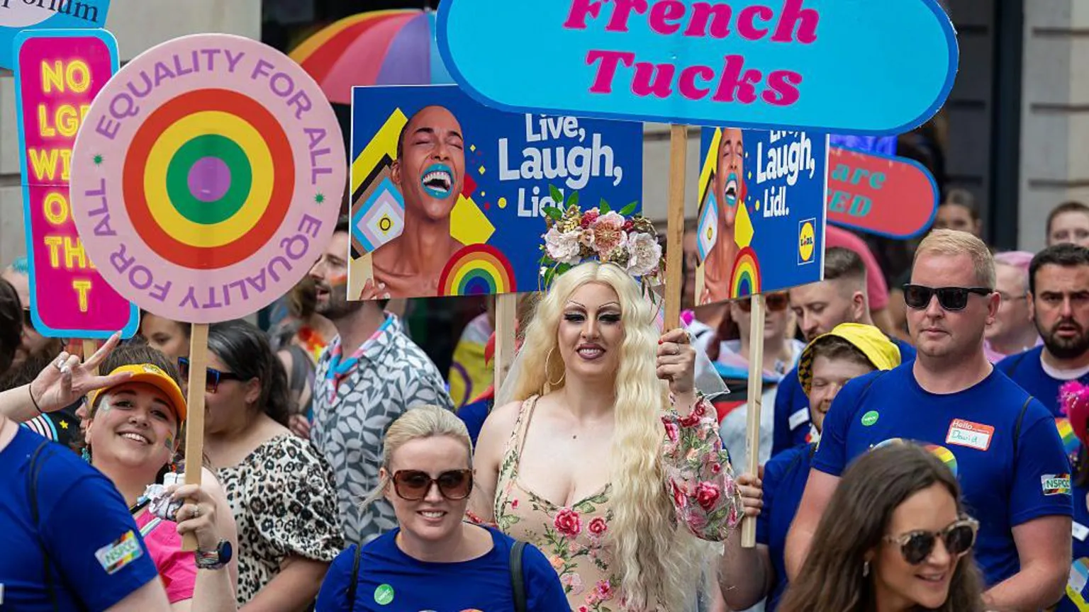 Crowds holding varuois placards during Pride Cymru parade.