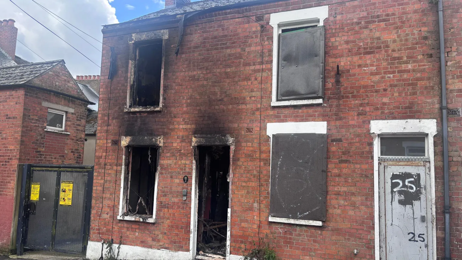 A red-bricked house has been burnt out/boarded up.