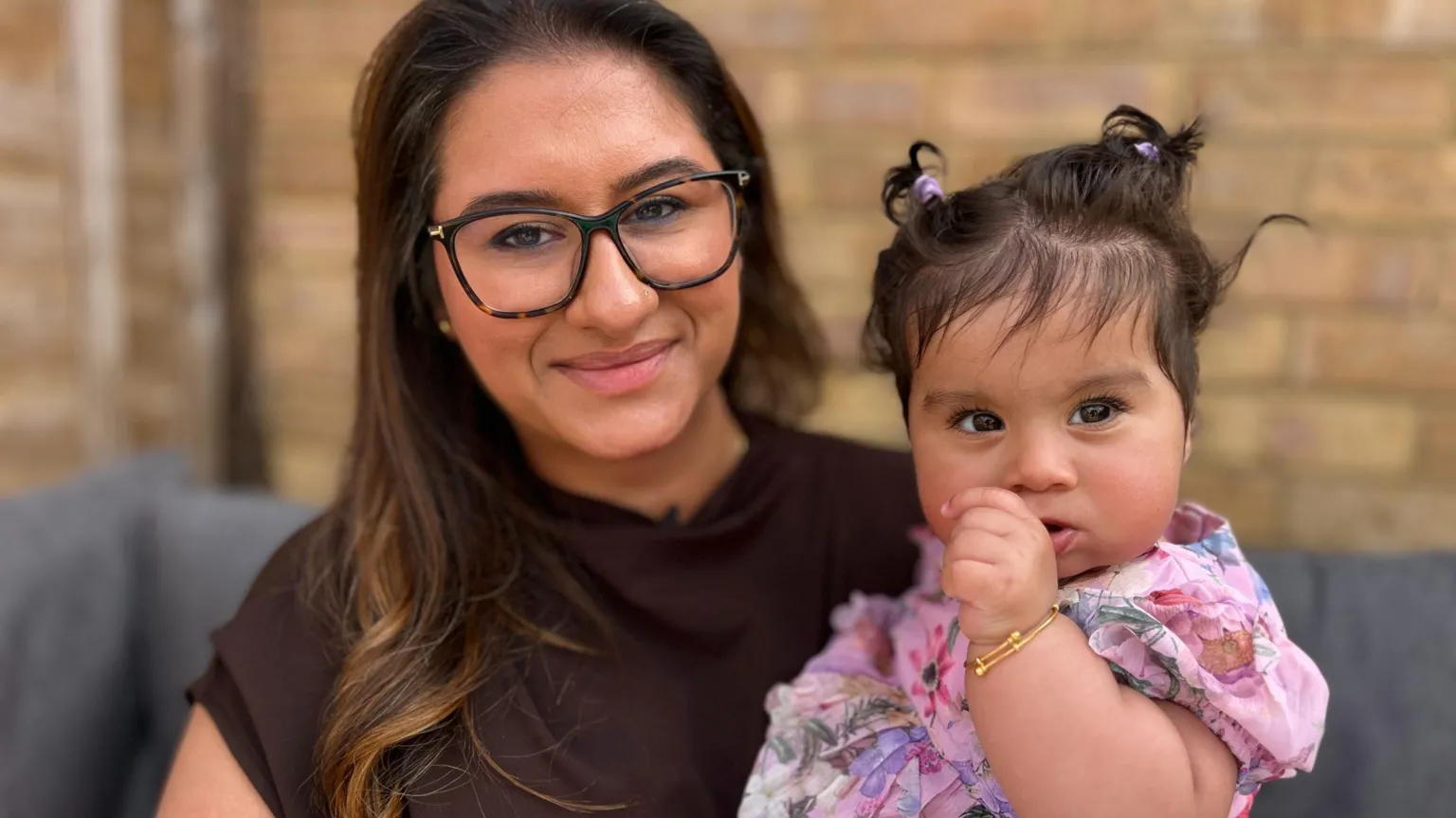 BBC/Martin Giles Amisha smiles at the camera while holding her daughter