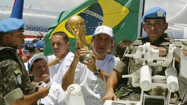 The Brazil team show off the World Cup trophy in Haiti in 2004, they are escorted by UN peacekeepers