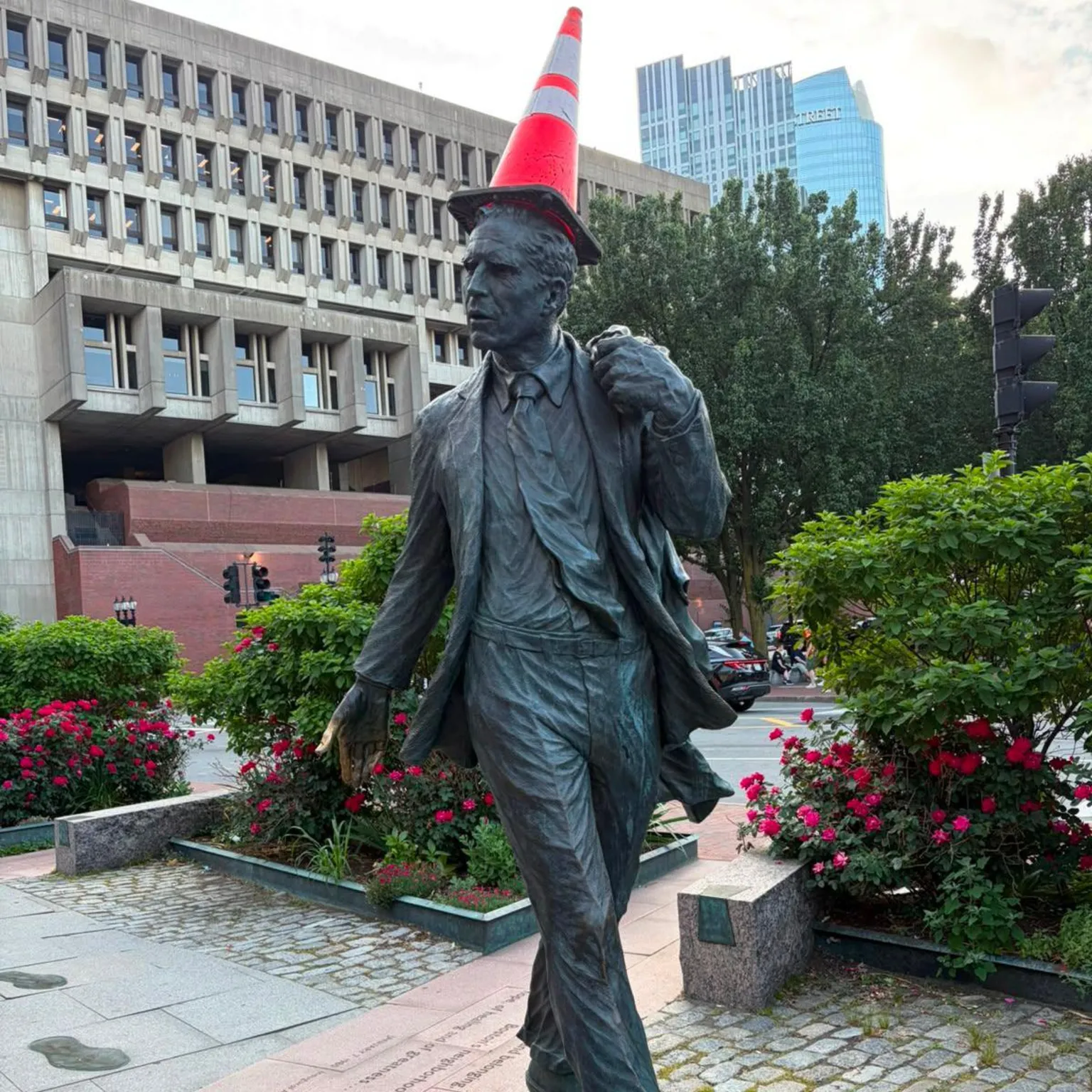 A statue of a man with a traffic cone place on its head.