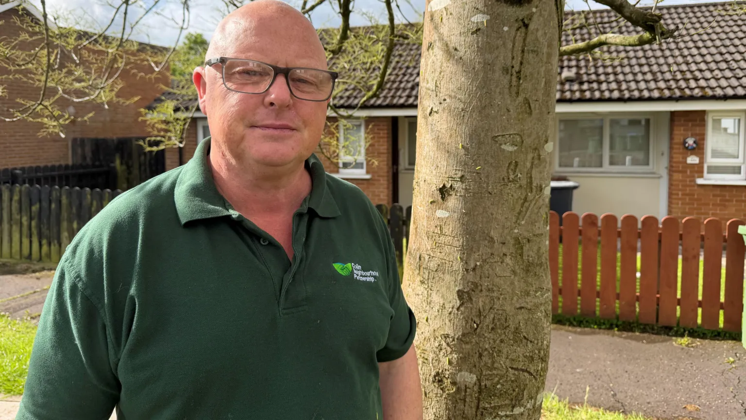 A man with glasses, he is wearing a green polo