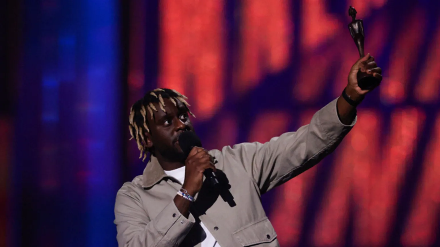  Myles Smith wears a white t-shirt with a grey jacket as he gives a speech and receives the Rising Star award at the Brit Awards at the O2 Arena in London, Britain, March 1, 2025.