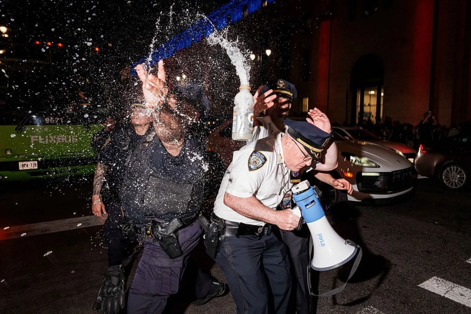 NYPD officers duck as an open bottle of liquid is thrown towards them in New York City.