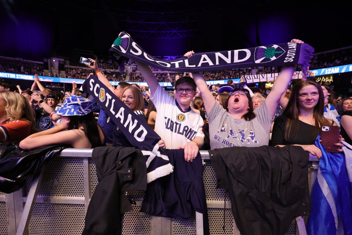 Fans cheering and holding up a Scotland scarf