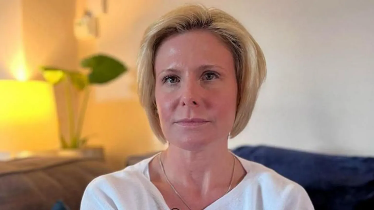 Kirsty Guest sits on a sofa with a light behind her.