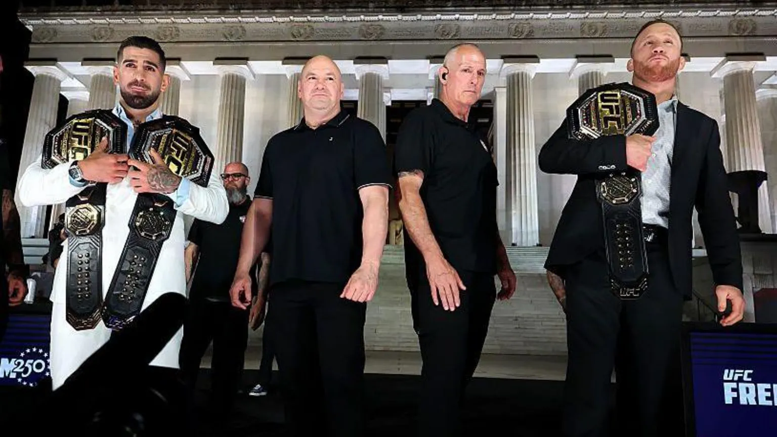 Zuffa LLC via Two fighters holding UFC belts standing beside others in front of the Lincoln Memorial