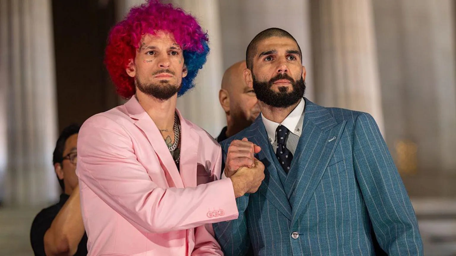 Anadolu via Two fighters - one with pink and blue hair wearing a pink suit and another wearing a pinstripe suit - bumping fists in front of the Lincoln Memorial