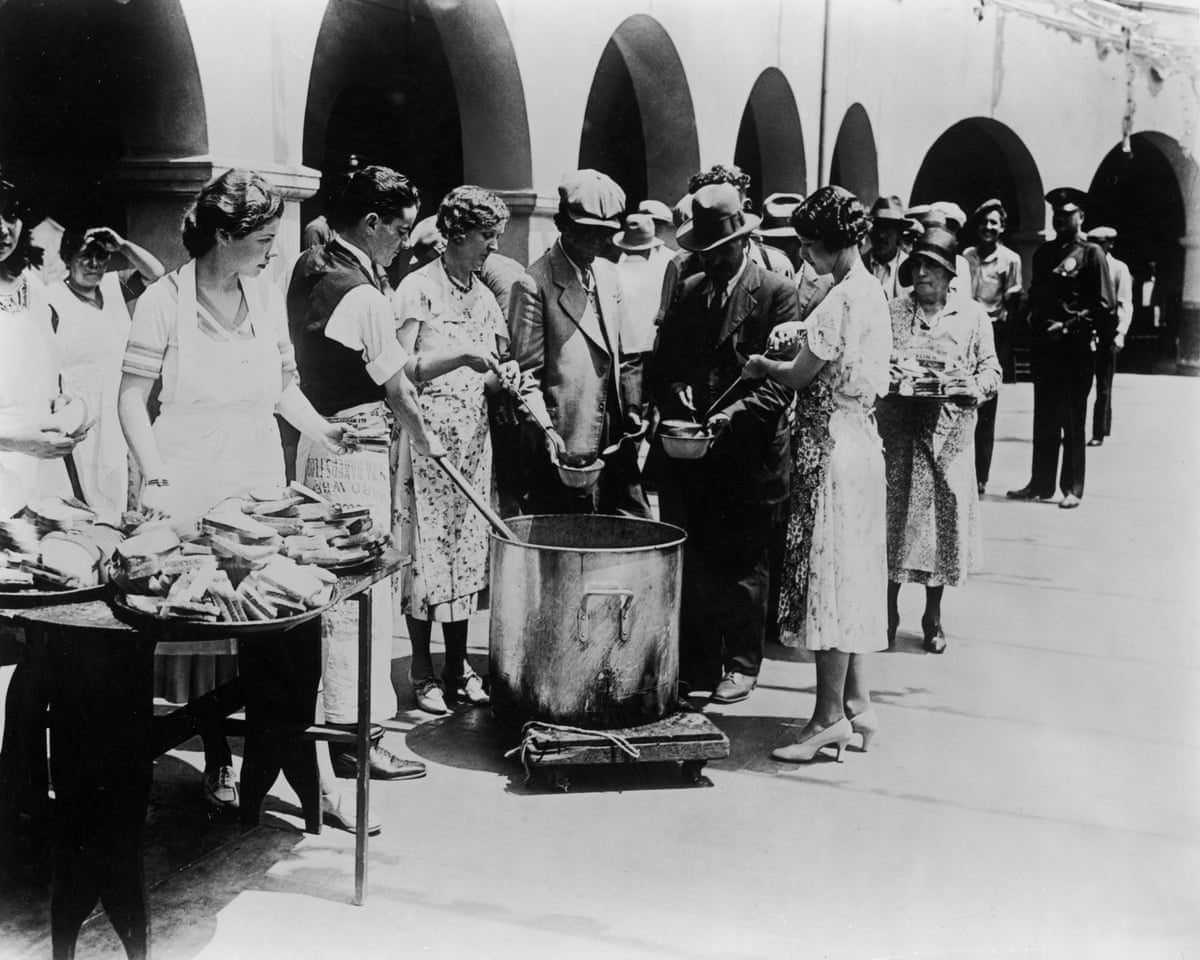 Unemployed men receiving soup and slices of bread at an outdoor breadline during the Great Depression in Los Angeles, California. Some women serve the soup with large ladles while others hand out slices of bread from trays