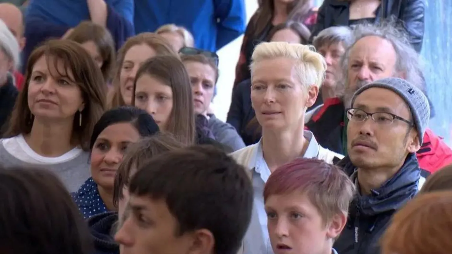Actress Tilda Swinton in an audience watching a graduation ceremony.