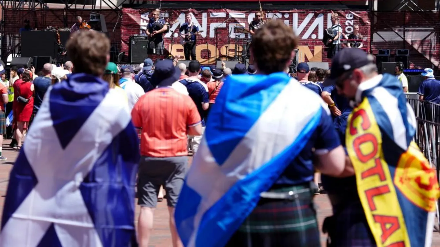Fans with Scotland fans watching a concert. There is a band on stage