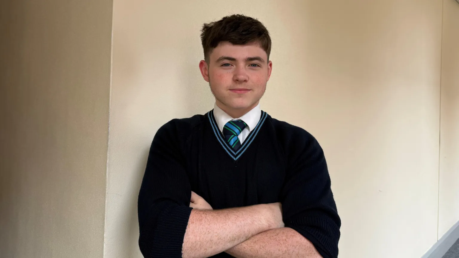 Shea. He has dark brown hair, wearing a navy school uniform.