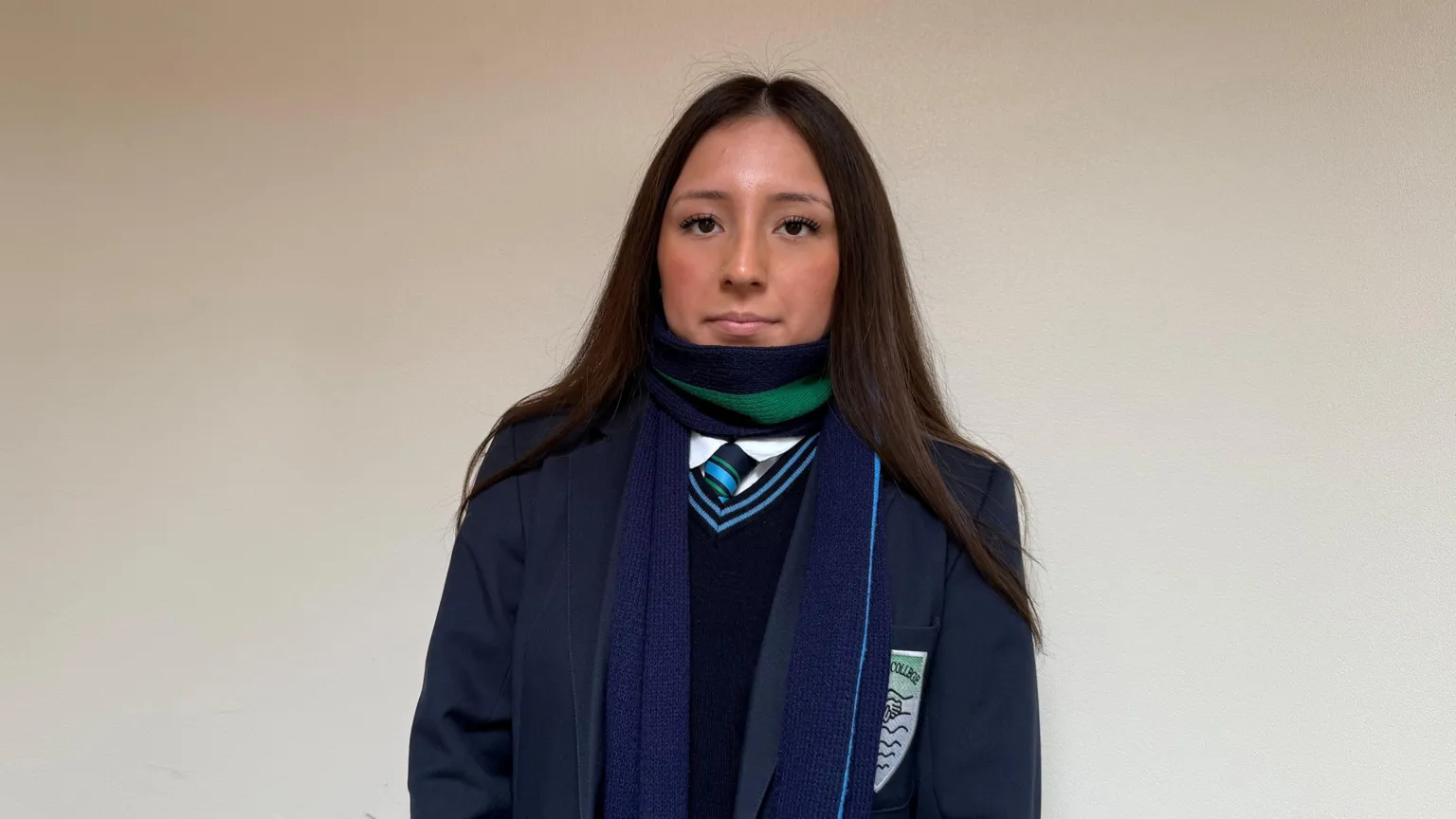 Sophia. She has long dark hair, wearing a green and navy scarf and a navy school uniform.
