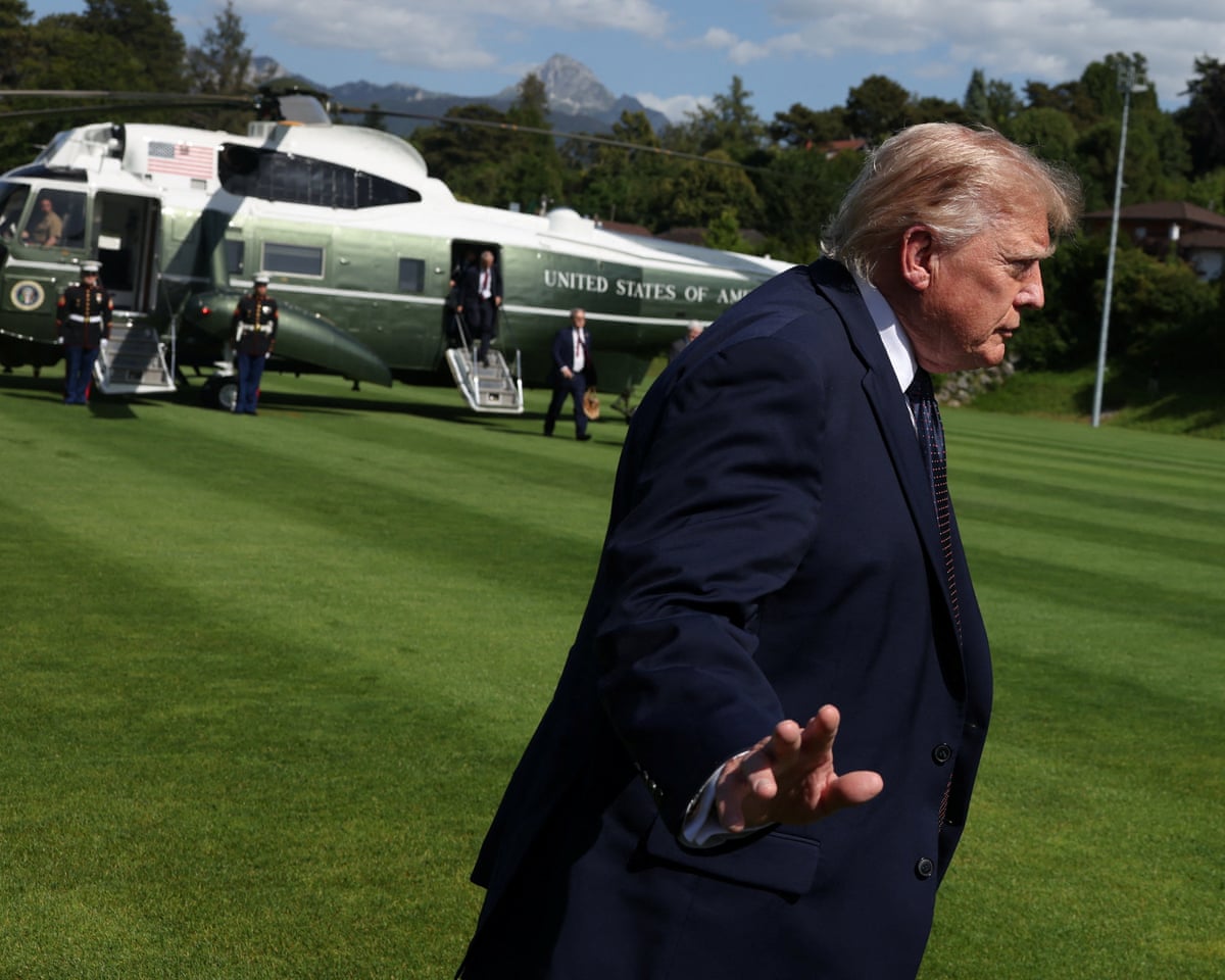 Donald Trump arrives to attend the G7 summit, in Evian-les-Bains, France. He gestures to the media, his helicopter is in the background.