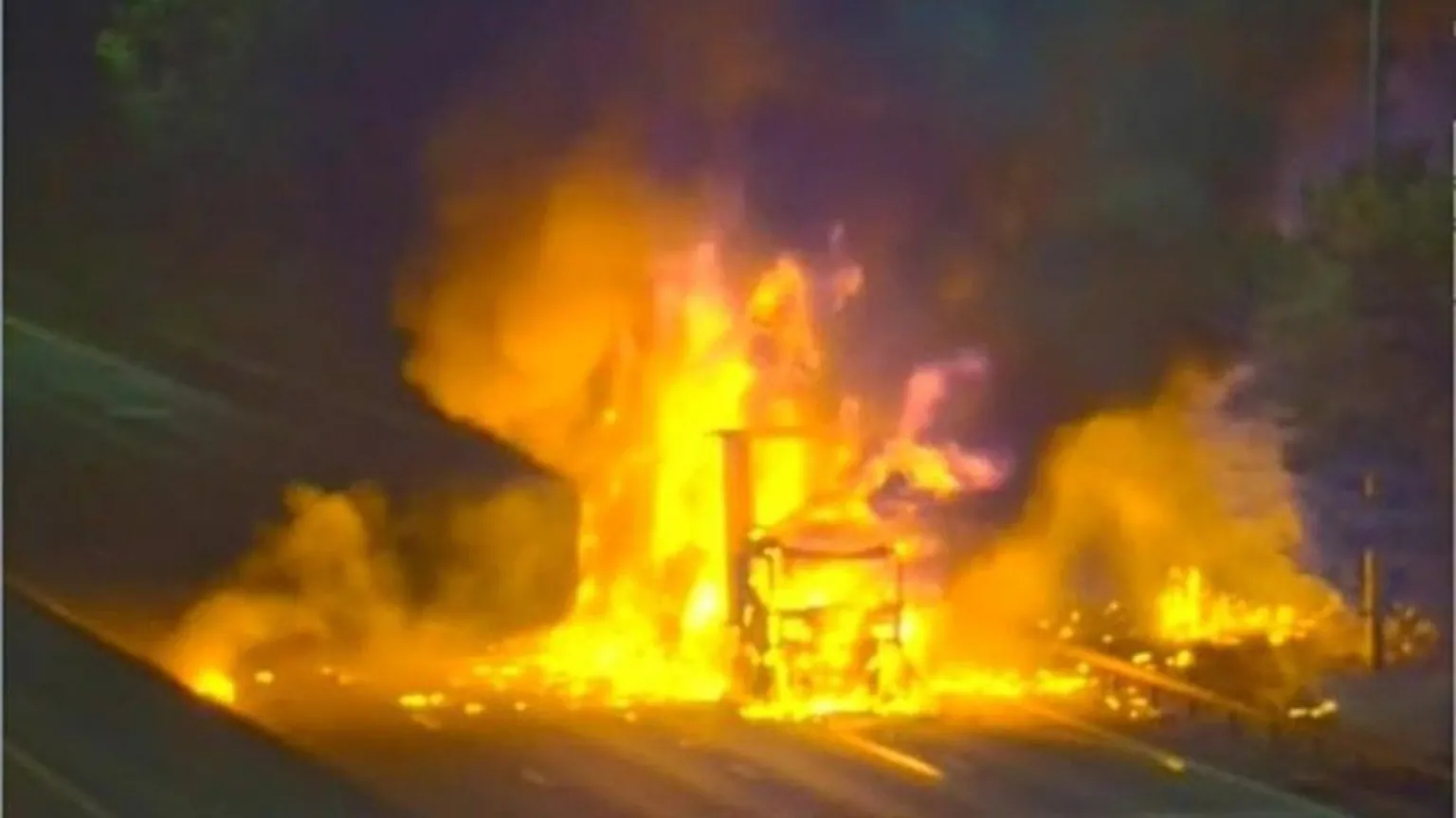 National Highways A lorry on fire on the M25, showing a burned-out vehicle, the rest of the image is blurred.