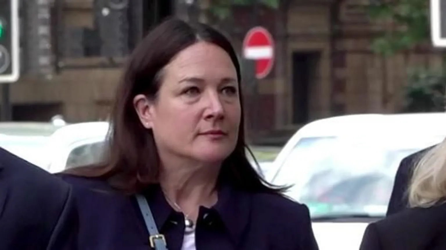  A middle-aged woman with long dark hair outside a court
