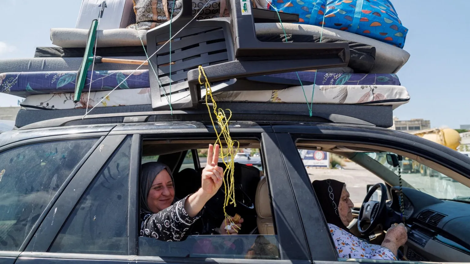  A displaced Lebanese woman smiles and gestures as she sits inside a car with her relatives during their journey home, on the highway near Sidon, southern Lebanon (16 June 2026)