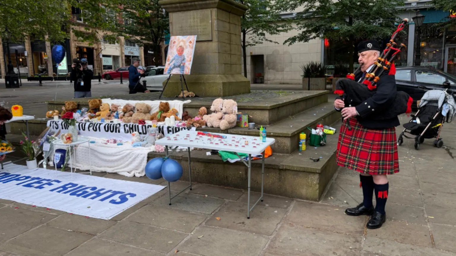 A piper wearing a traditional tartan kilt plays the bagpipes at the start of a candlelight vigil for murdered baby Preston Davey at Preston's Flag Market.