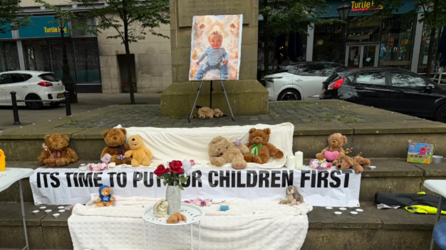 Teddies are left for Preston Davey near a picture of the murdered 13-month-old by the Cenotaph before a vigil is held in his memory on Preston's Flag Market