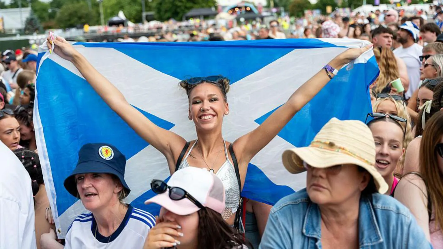  A smiling woman holds up a Saltire while in the crowd at a music festival