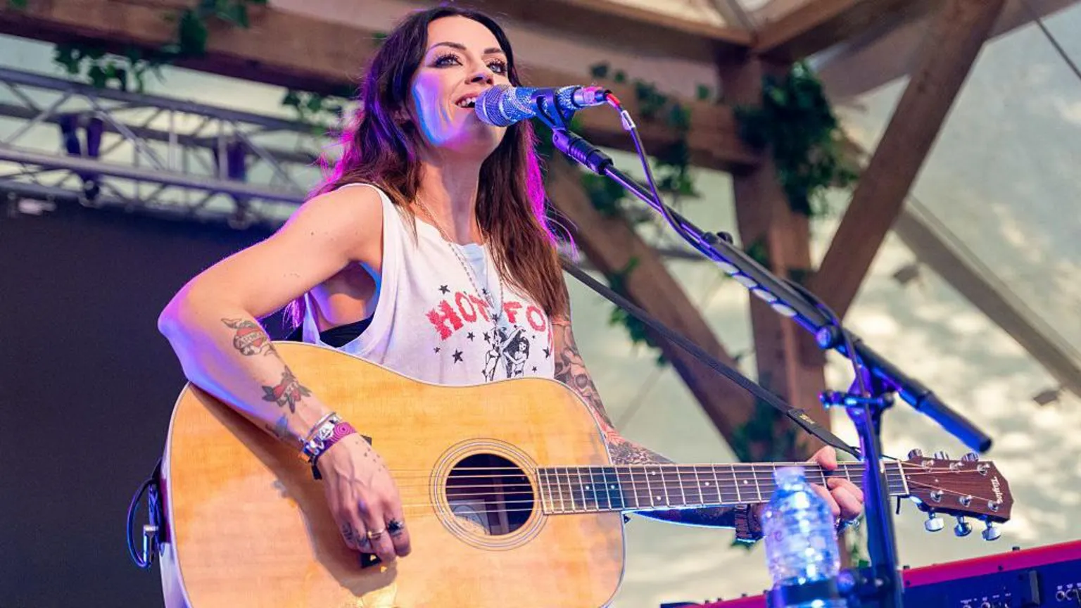 Amy Macdonald on stage. She has a white T-shirt on and is playing an acoustic guitar 