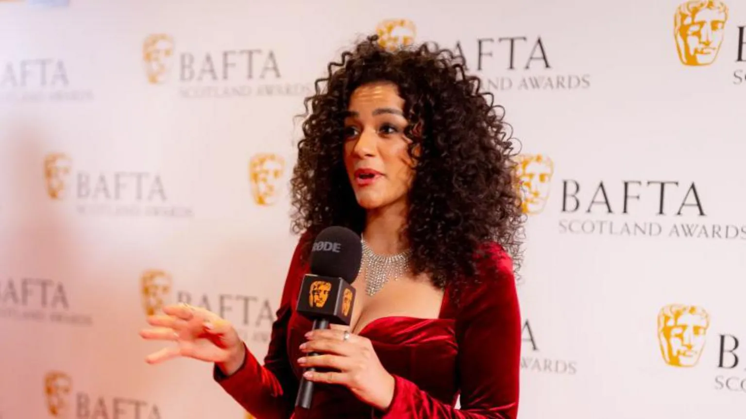  Shereen Cutkelvin on the red carpet - she is wearing a red dress and holding a microphone