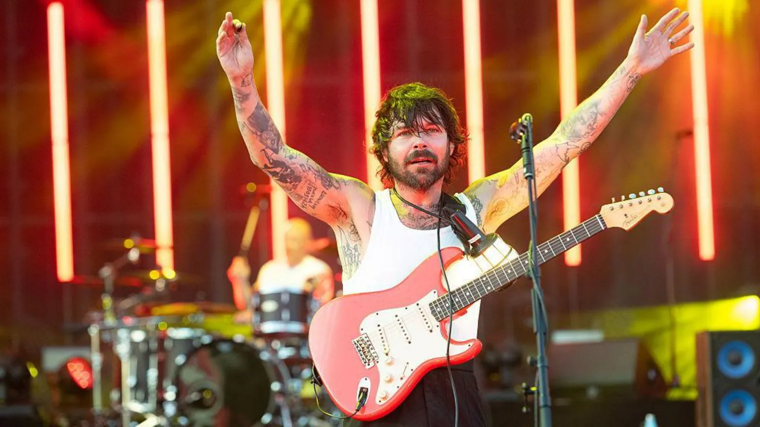  Simon Neill of Biffy Clyro onstage. He has a guitar strapped on and his hands in the air.