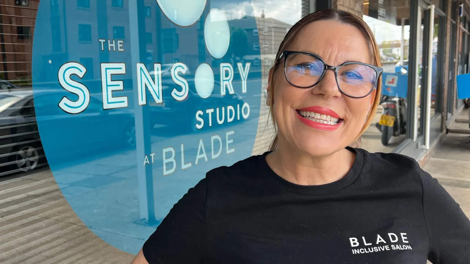 John Fairhall/BBC A head and shoulders image of a woman wearing a black top with the words Blade Inclusive Salon on it. She is looking into the camera.