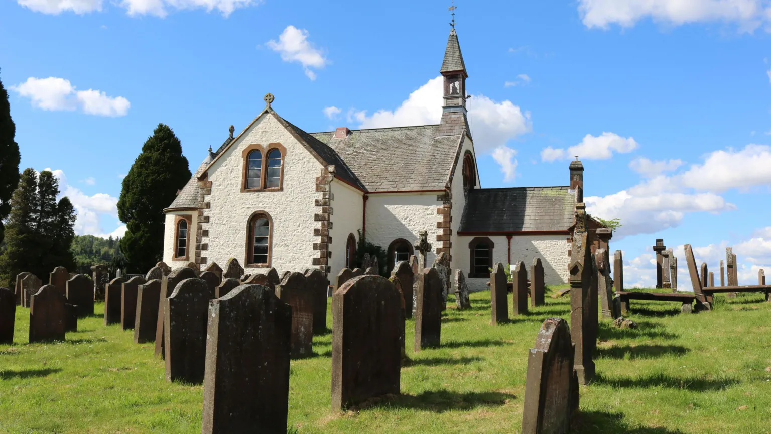 Billy McCrorie An old church building in white with brick edges and a line of gravestones in front on green grass