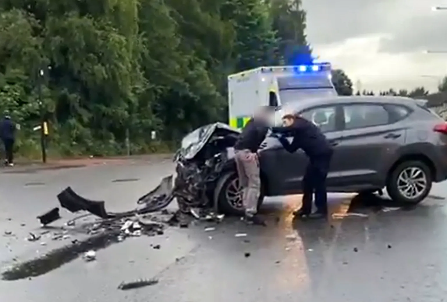 Two people stand next to a smashed up car
