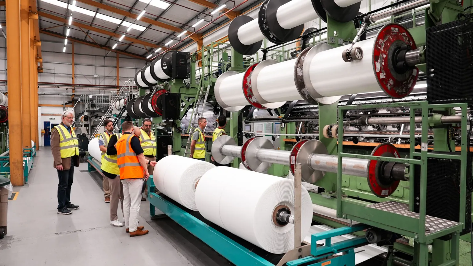 HFL/SCM Huge reels of yarn are seen stacked on spools to the right while on the left delegates examine them.