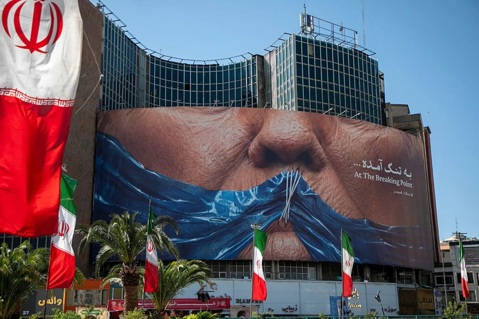  A poster in Tehran depicts the mouth of U.S. President Donald Trump, gagged by a blue ribbon in the shape of the Strait of Hormuz, on May 9, 2026 in Tehran, Iran