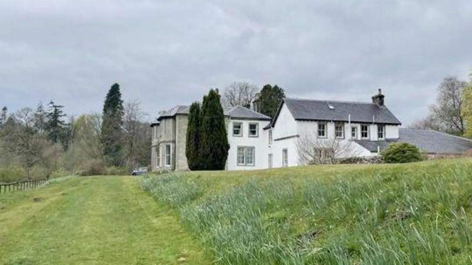 Buccleuch A side view of Irvine House a white and granite mansion house surrounded by grass and trees