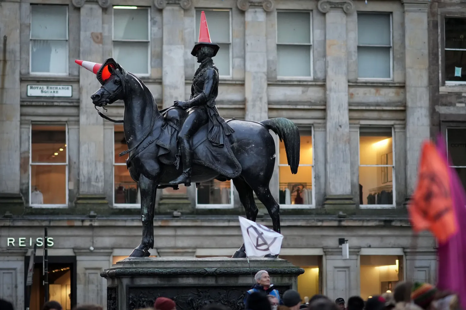 A statue of the Duke of Wellington riding a horse in Glasgow city centre - both man and horse have traffic cones on their heads