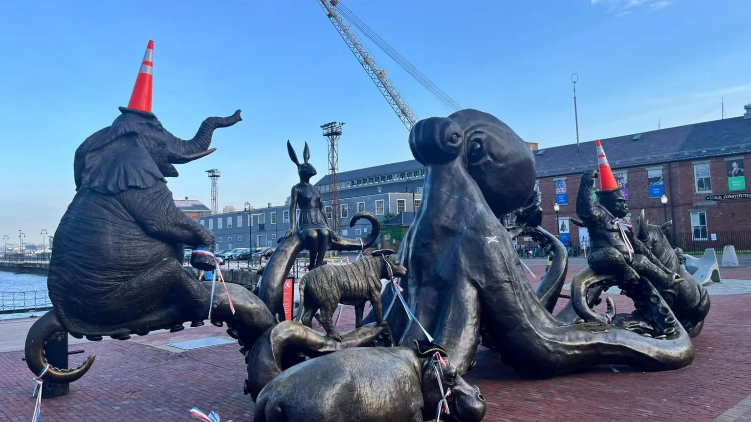 Statues of different animals in Boston with orange traffic cones on their heads.