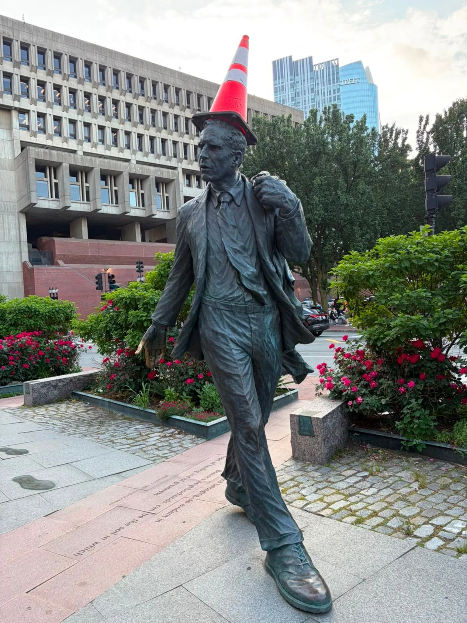 A statue of a man with a traffic cone on its head.