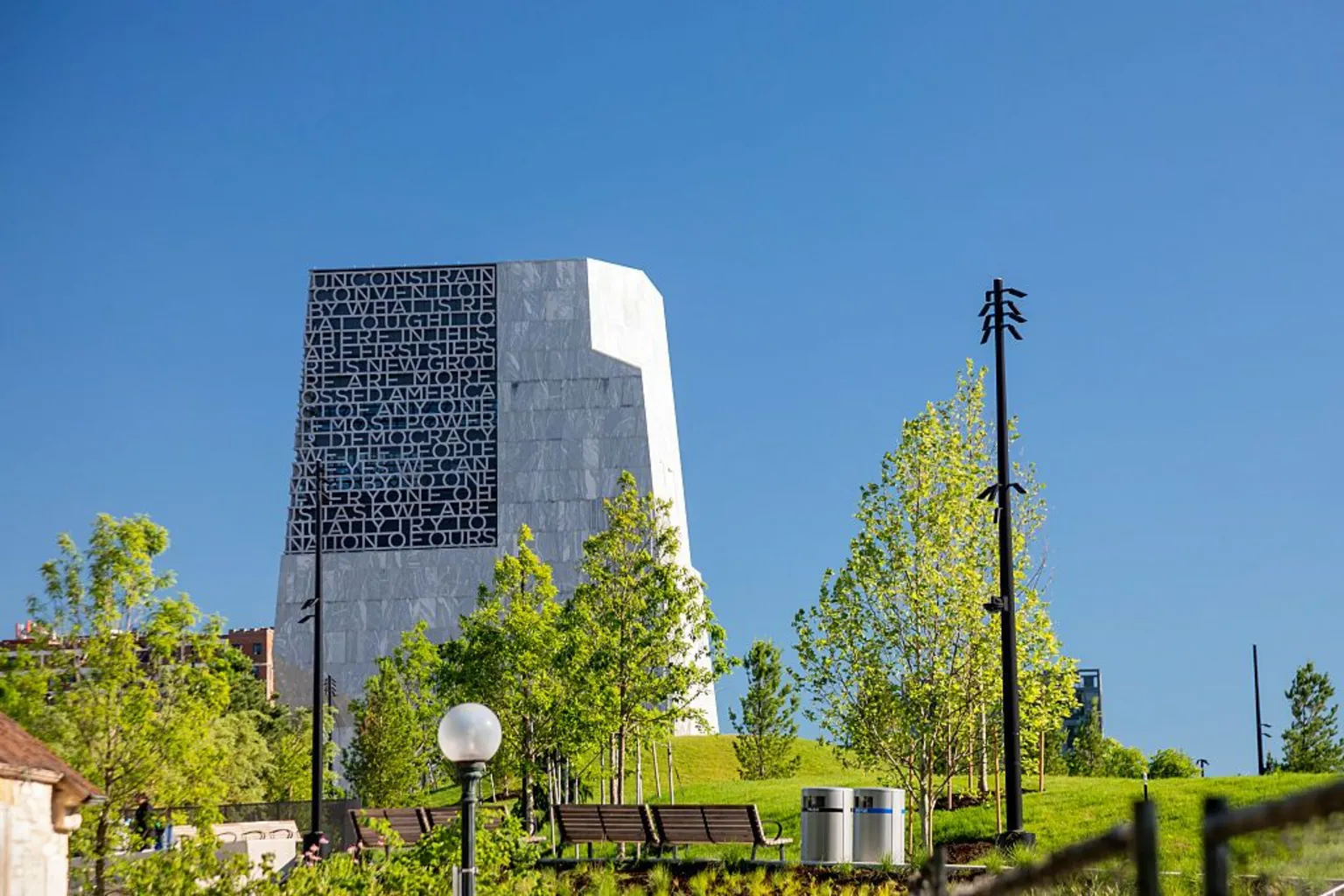 Universal Images Group via The Obama Presidential Center, a large modern stone building, rises over a lush green park and benches in Chicago.