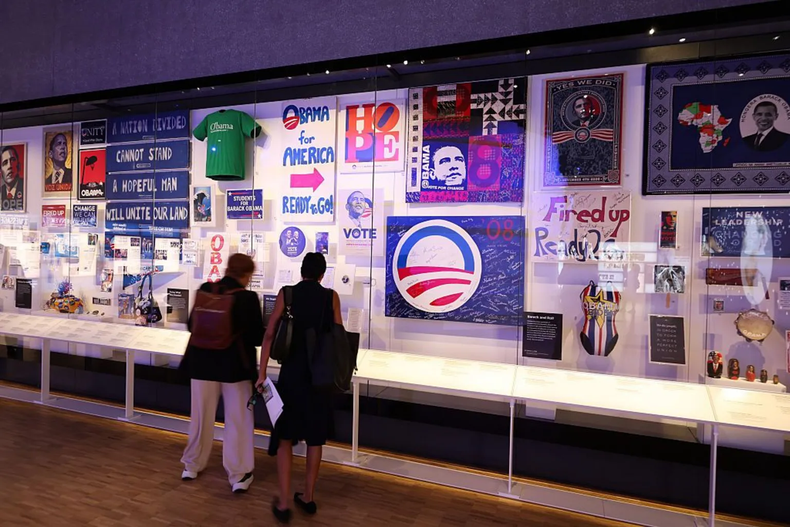 Talia Sprague/Bloomberg via People stand and look at an exhibit of campaign merchandise and supporter-made memorabilia from Obama's presidential campaigns.