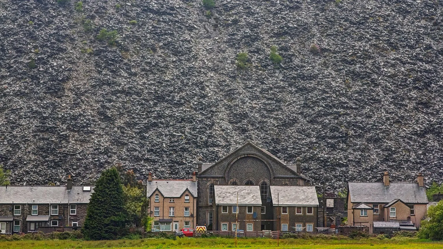 Getty The slate landscape of Blaenau. In front of the old slate clifftops is a row of terraced houses with pitched roofs.