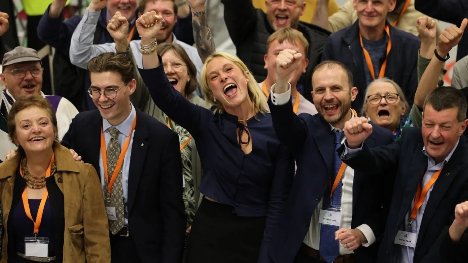  A group of people in business attired cheer with their fists raised. 