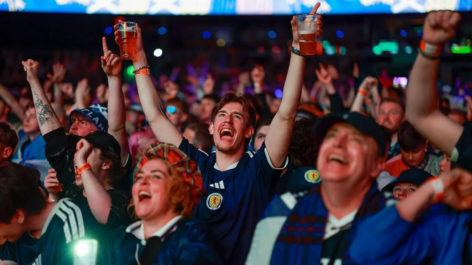  Scotland fans punch the air and celebrate while watching a football match in an indoor fanzone.