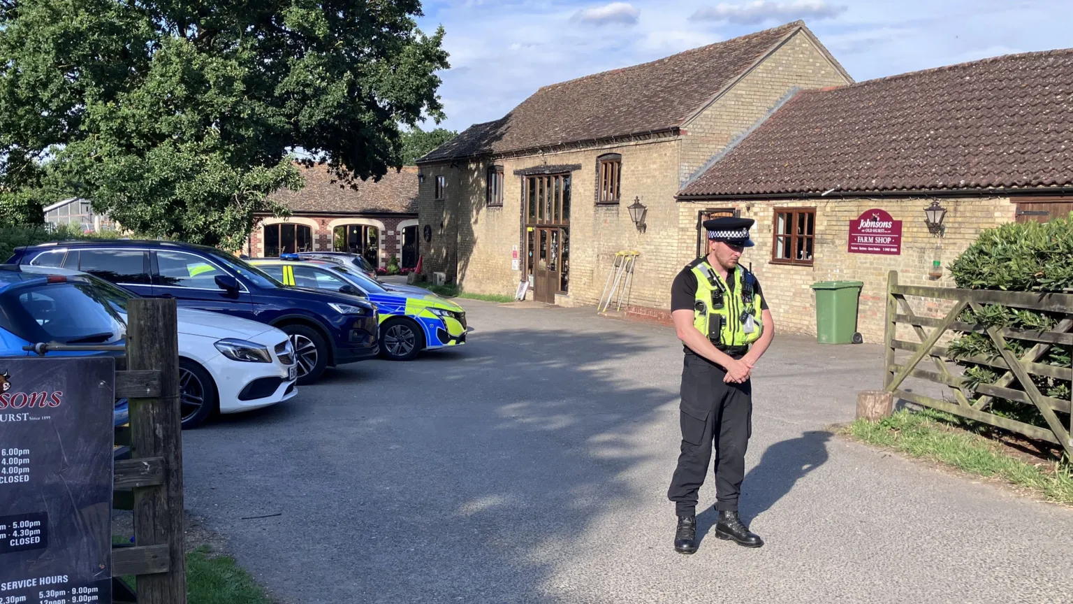 Sam Read/BBC A uniformed police office stands in front of a bricked barn has a car park outside the front on the left. There is a fence on the right which opens into a court yard and there are signs on the door. There is a police car parked in the car park.