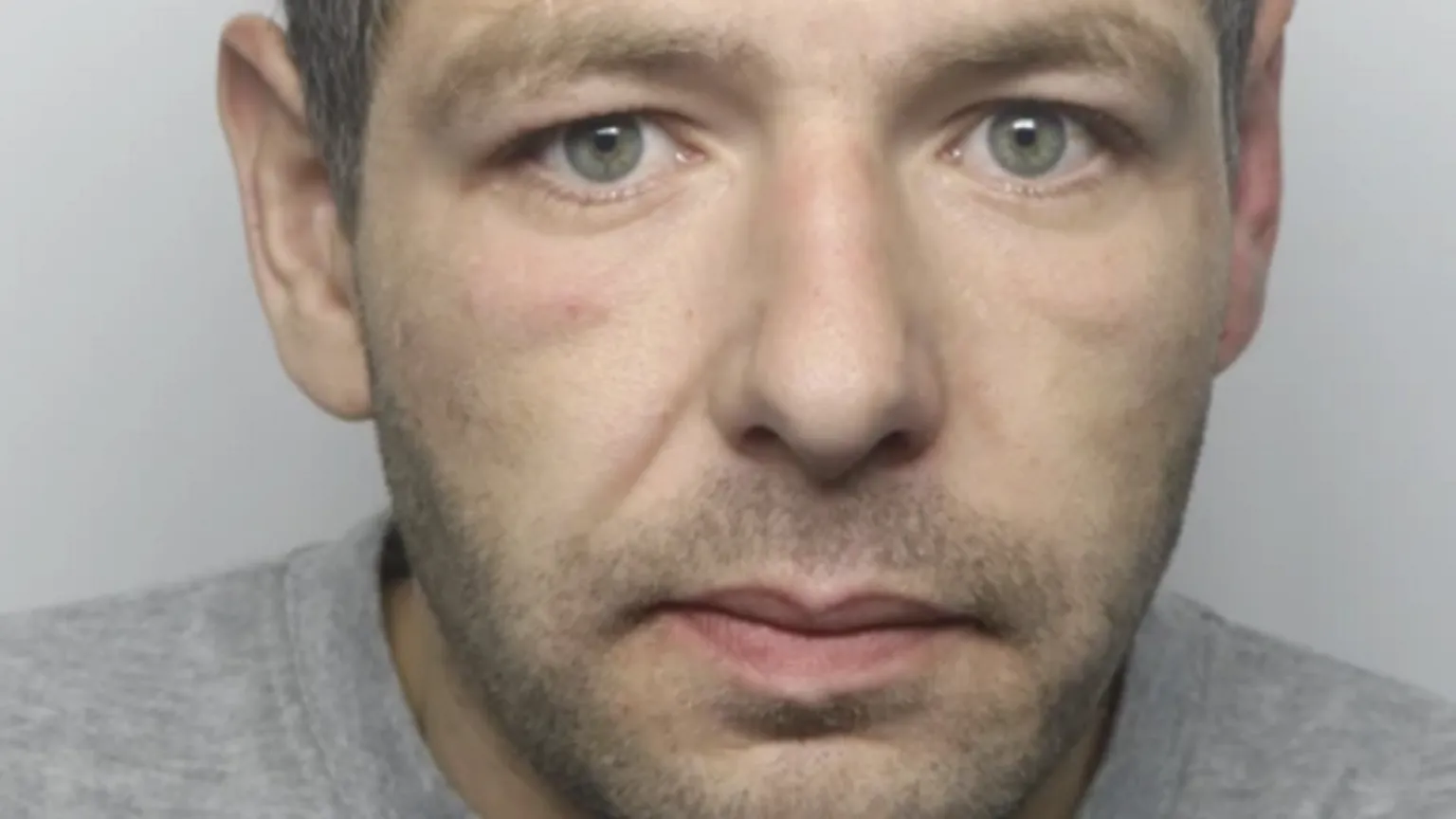 Dyfed-Powys Police Police custody shot of a man with a short beard, wearing a grey jumper.
