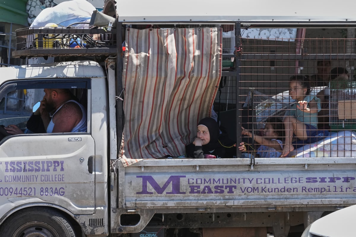 Two children sat in the back of a van with their belongings.