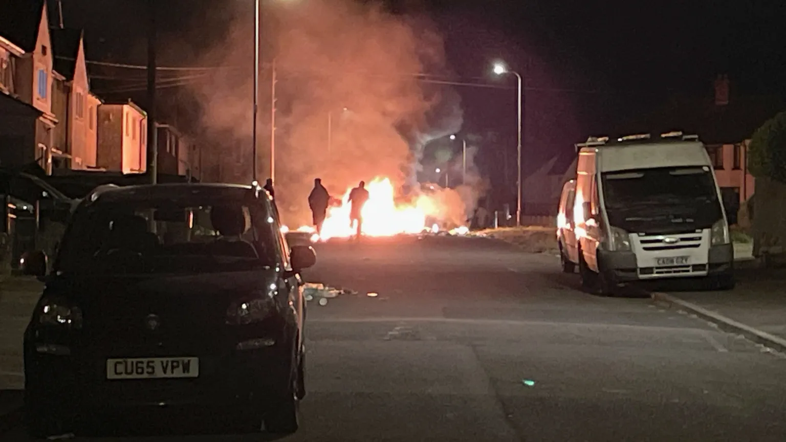  A fire in a dark street with people in front of it