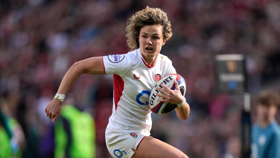 Ellie Kildunne running with the ball under her left arm as she looks to her right, during a game for England at the Women's Six Nations