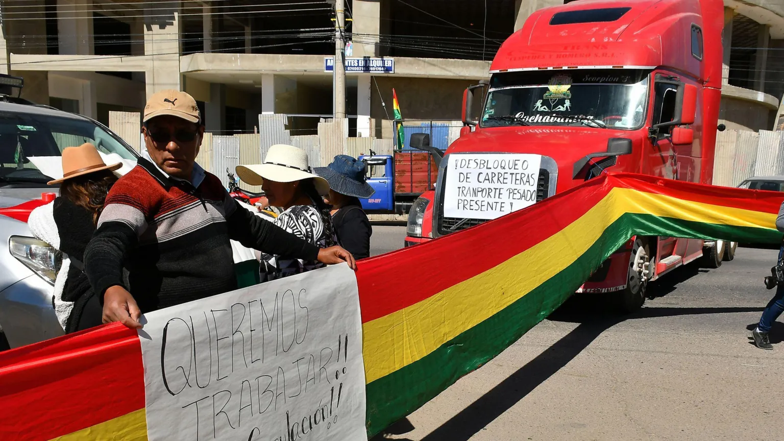 EPA Protesters hold a flag and sign next to a road block with several vehicles