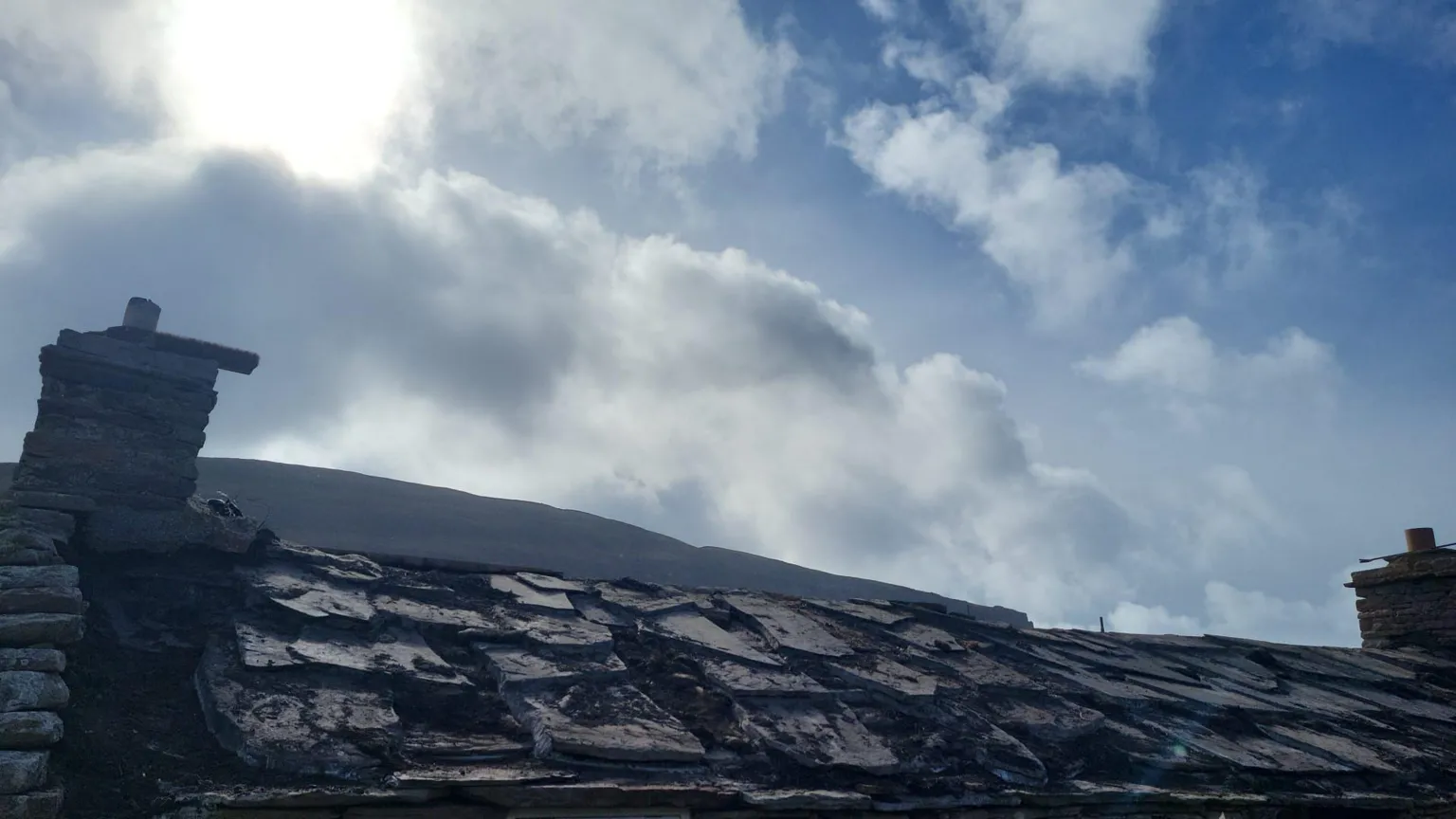 Graham Brough A dilapidated-looking roof sits at the foreground of the photograph on a sunny day.