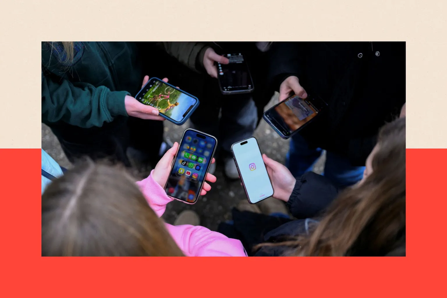 Teenagers standing in a circular formation while looking down at their mobile phones, in Bonn, Germany. Their faces are concealed. In the foreground is a girl with brown hair and wearing a pink top. The others wear darker clothing.