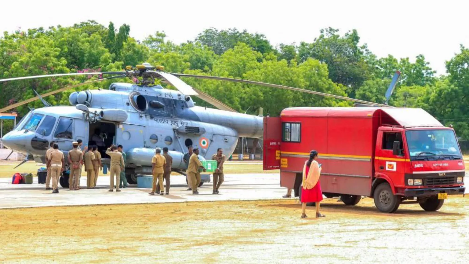 Officials carry a big green box from a grey helicopter to a red van.